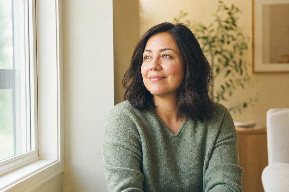 Woman at home in Texas in recovery, hopeful and looking out a sunlit window