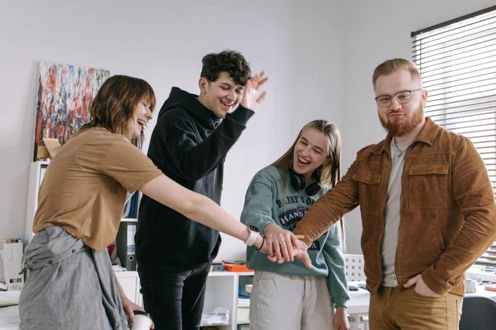 A group of cheerful young colleagues celebrating with a team hand stack indoors at a supportive outpatient program