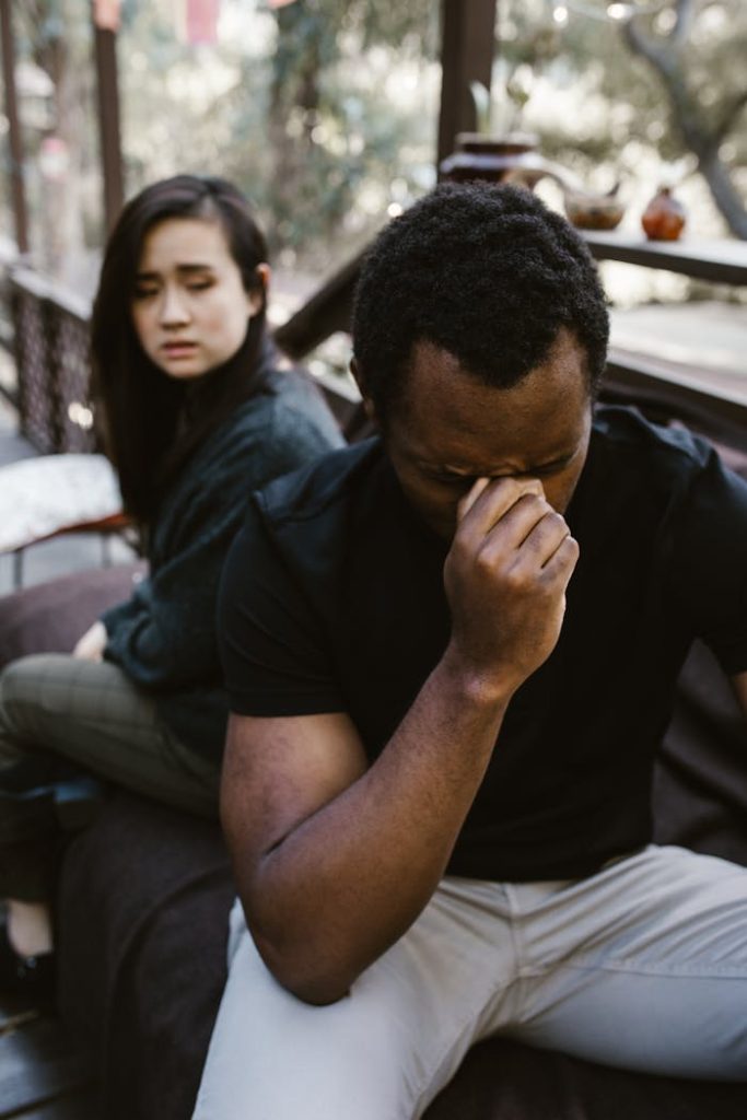A man and woman sit apart, capturing a powerful moment of grief and reflection.