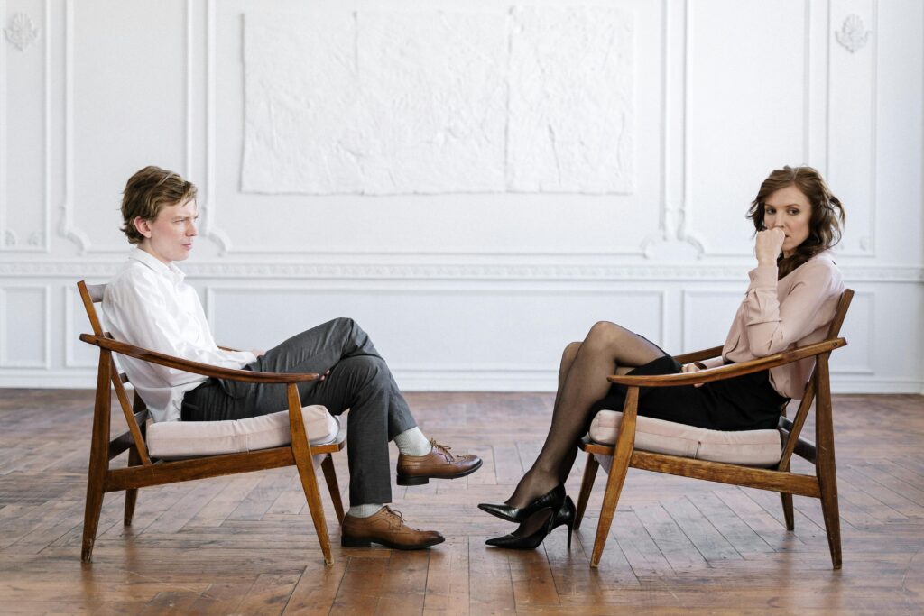 Two people sitting across from each other in a modern therapy space, symbolizing whole-person recovery care