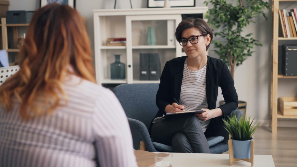 A recovery coach in a one-on-one session guiding a client through goal-setting and support strategies