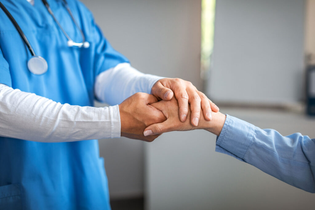 Healthcare professional offering support through hand-holding, symbolizing compassionate outpatient care at Altura Recovery for addiction and mental health treatment.