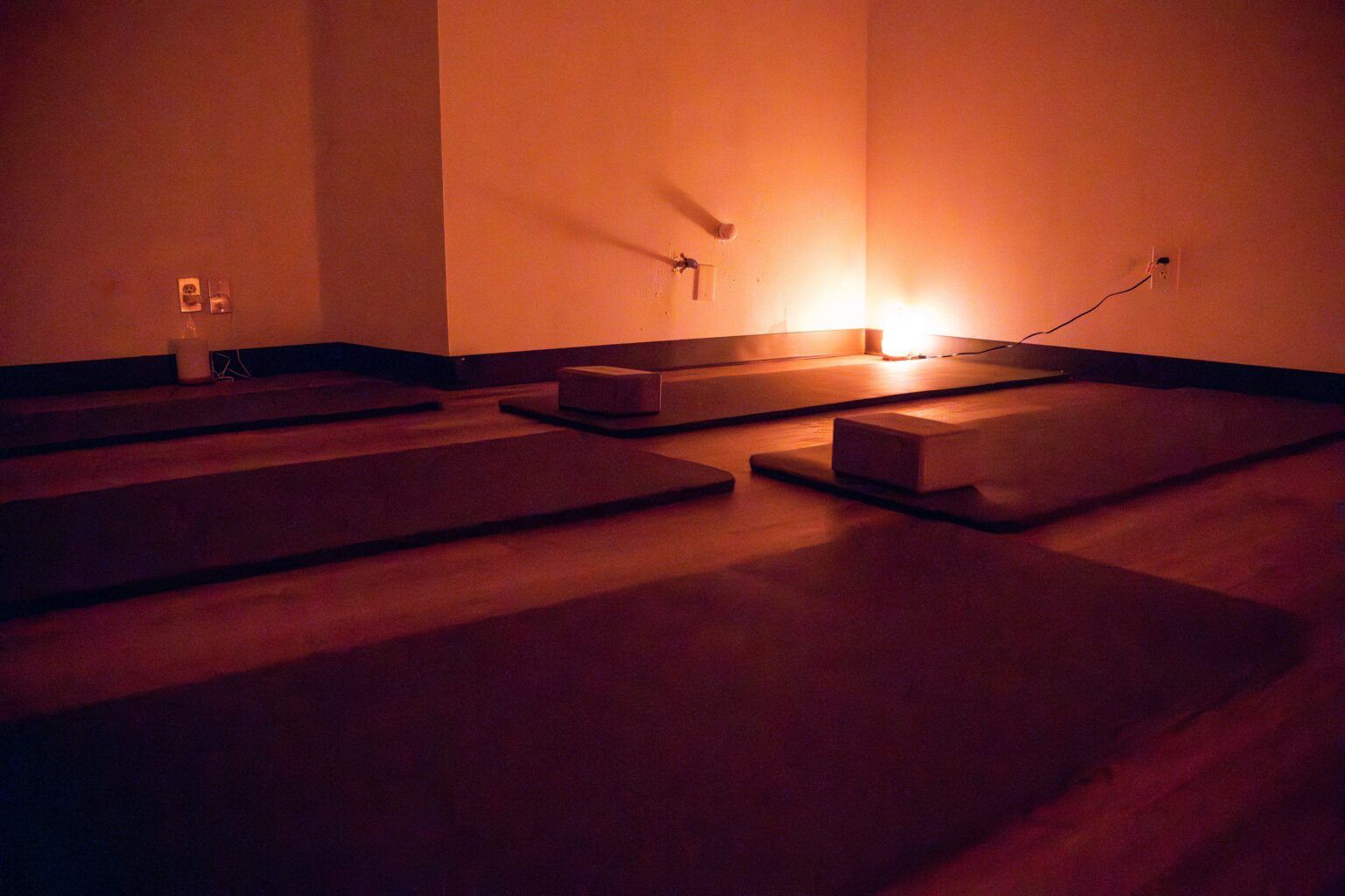 Yoga and meditation room with dim lighting, yoga mats arranged for sessions, and blocks for support, reflecting a calming environment for recovery at Altura Recovery's Intensive Outpatient Program.