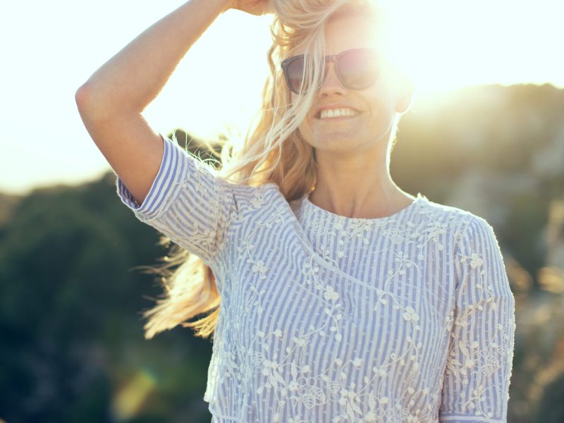 Young caucasian blonde woman playing with hair in sunset