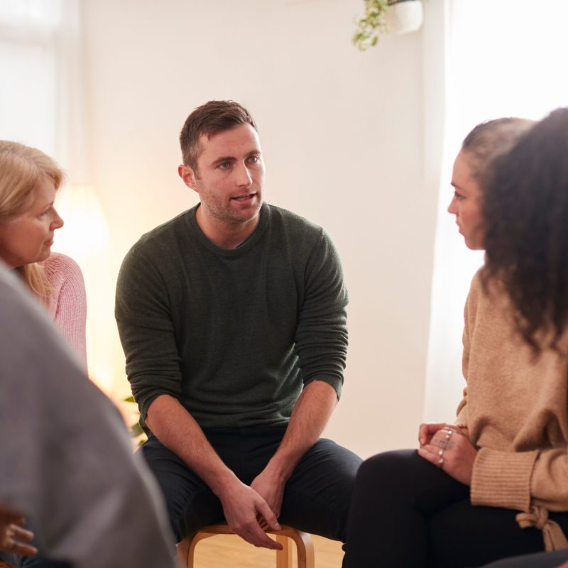 Man Speaking At Support Group Meeting For Mental Health Or Dependency Issues In Community Space